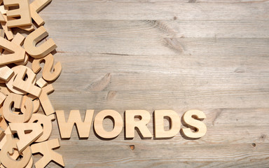 Word words made with block wooden letters next to a pile of other letters over the old wooden planks surface composition