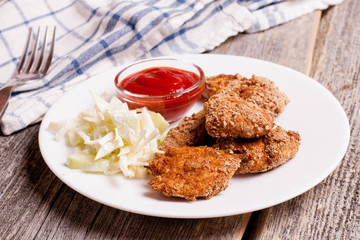 chicken nuggets with tomate sauce and vegetables on wooden board