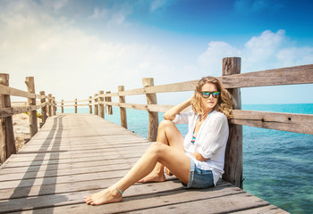 attractive young woman with curly hair  sits on a wooden bridge