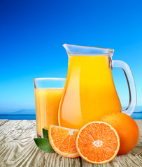Jug or pitcher with highball of orange juice with oranges