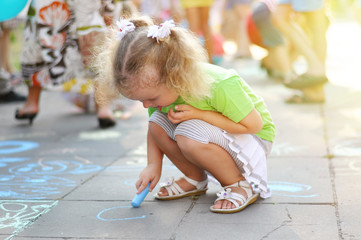 little girl draws a chalk on asphalt
