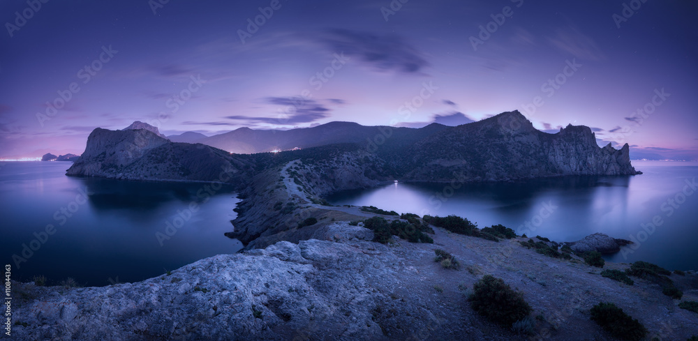 Wall mural night landscape with mountains, sea, starry sky and city lights. amazing view with rocks at dusk in 