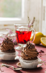 Chocolate cupcakes with chocolate cream and red floral tea with lemon