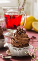 Chocolate cupcakes with chocolate cream and red floral tea with lemon