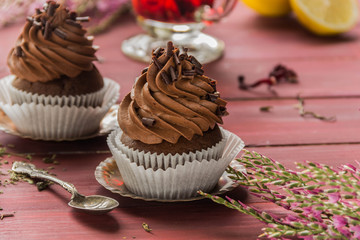 Chocolate cupcakes with chocolate cream and red floral tea with lemon