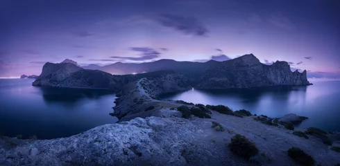 Poster Nachtlandschap met bergen, zee, sterrenhemel en stadslichten. Prachtig uitzicht met rotsen in de schemering op de Krim © den-belitsky