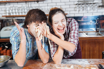 Funny couple with flour on faces having fun using dough