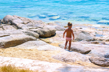 Little girl walking on the sea shore. Happy in summer vacation o