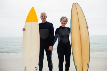 Portrait of senior couple with surfboard 