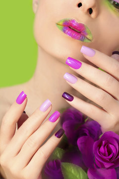 Colorful lilac manicure and lips on a girl with roses on a green background.
