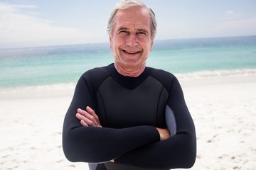 Portrait of happy senior man standing with arms crossed on the beach
