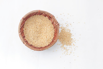 Millet, bird's food inside a wicker basket and some scattered outside the basket on isolated white background