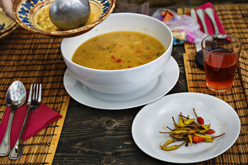 Bean soup in bowl with fresh sliced bread on napkin, on wooden t