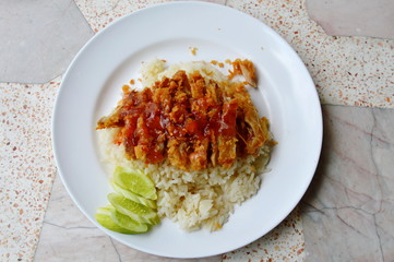 fried chicken on steamed rice dressing sweet chili sauce on dish