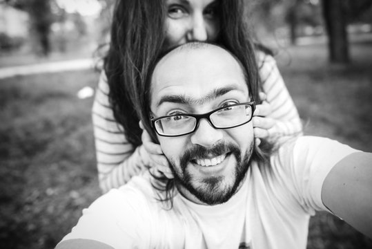 ? Handsome man with beard and young pretty cheerful girl with glasses making selfie.