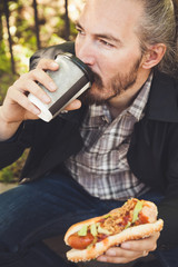 Bearded Asian man having lunch with hot dog