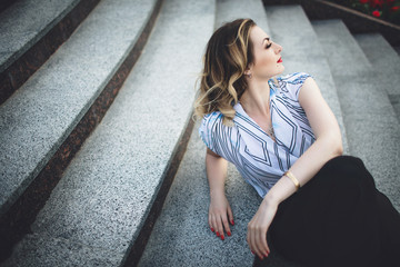 interesting young lady sitting on stairs and posing for the came