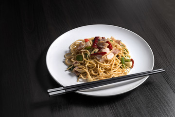 Spaghetti with ham chili sauce on a dark wood plank

