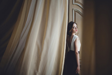 frail woman standing on the background of beautiful wall