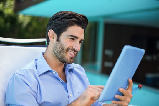 Smart man using digital tablet near pool