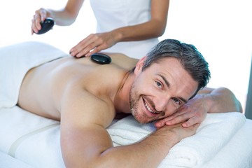 Fototapeta na wymiar Man receiving a hot stone massage from masseur