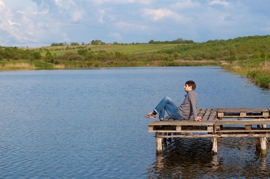 Man sitting on the pier of a lake