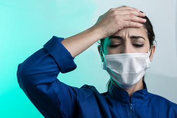 medico con camice blu e mascherina bianca  si tiene la testa in segno di disperazione - sfondo verde