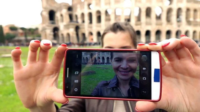 Young tourist taking photo with cellphone standing close to the Colloseum, super slow motion
