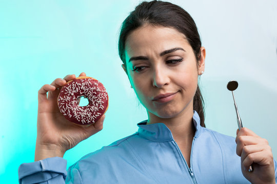 una dentista con specchietto guarda con aria di diffidenza una ciambella