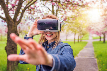Woman wearing virtual reality goggles outside in spring nature