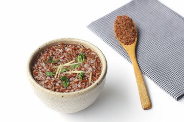 gruel (brown rice) in ceramic bowl and wooden spoon on napery isolated on white background