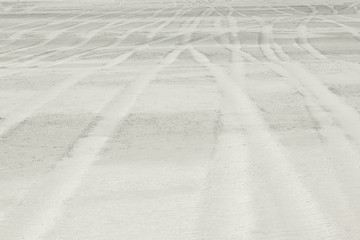 Background representing traces of automobile wheels on white san