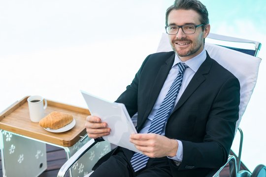 Smart man holding document near pool