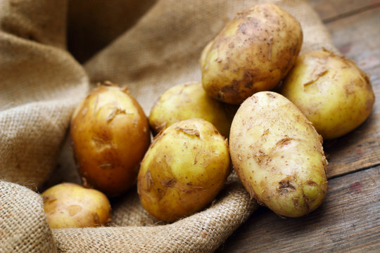 Raw potatoes on burlap background