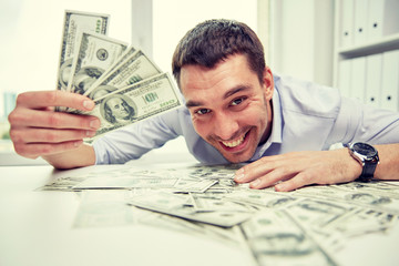 happy businessman with heap of money in office