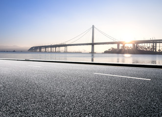 empty asphalt road with tranquil water and gold gate bridge at s