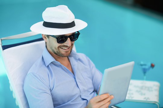 Smart man using digital tablet near pool