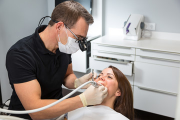 Dentist treating patient on chair with a dental drill
