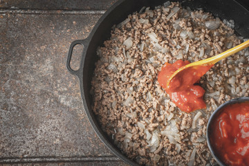 Fried minced meat with onion and chopped tomatoes  in the pan top view