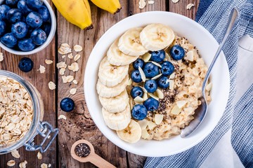 Breakfast: oatmeal with bananas, blueberries, chia seeds and almonds - obrazy, fototapety, plakaty