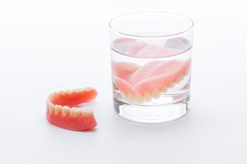 Full Denture in glass of water on white background