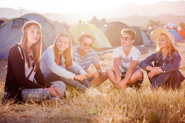 Teenagers sitting on the ground in front of tents