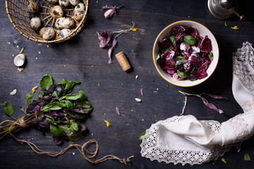 Fresh spring salad with basil, eggs, radicchio leaves and garlic on dark wooden table, top view.