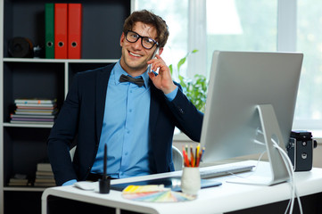 Handsome young man working from home office and using smartphone