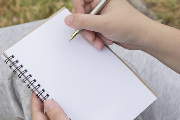Hand of a woman holding a notebook and pen to take notes.