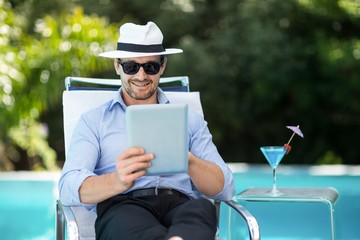 Smart man using digital tablet near pool