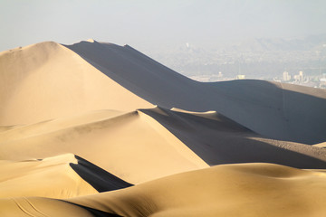 Fototapeta na wymiar Sand dunes nar Huacachina, Peru. Ica city in the background.
