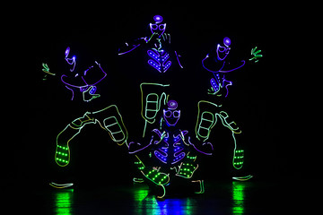 dancers in led suits on dark background, colored show