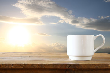 front image of coffee cup on table in front of sunset