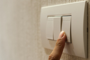 Closeup of A finger is turning on a lighting switch on wallpaper background with copyspce.